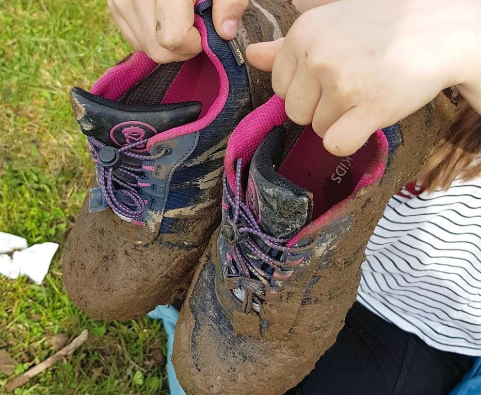 Turnschuhe eines Kindes, voll mit Schlamm